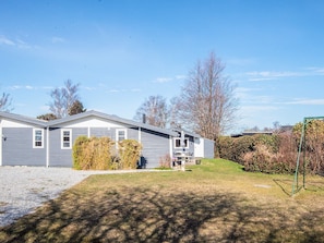 A single-story house with a front porch, a small deck, and a well-maintained lawn. - 4 Star Holiday Home in Grenaa (Grenaa)