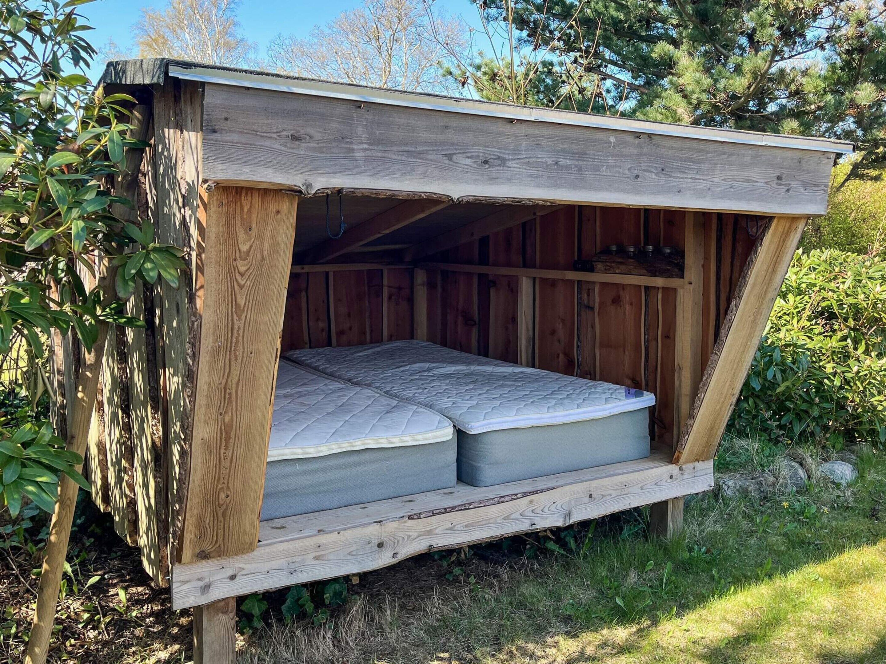 A wooden cabin with a loft-style bed, built-in shelves, and a sloped roof.