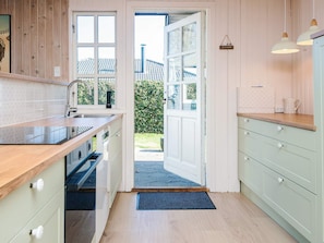 A kitchen with a wooden countertop, a sink, and a door leading outside. - 4 Star Holiday Home in Grenaa (Grenaa)