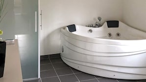 A modern bathroom with a freestanding bathtub, a glass shower enclosure, and a tiled floor.