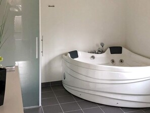 Ett modernt badrum med ett fristående badkar, en dusch med glasväggar och ett kaklat golv.