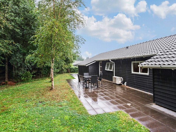 A residential property with a patio area, a small table and chairs, and a covered outdoor space.