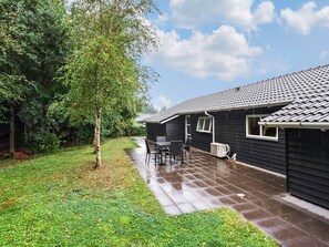 A residential property with a covered patio, a small outdoor seating area, and a garden.