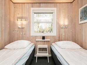 Quarto com duas camas, uma janela e uma estante com abajur.