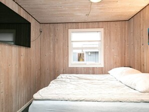 Un dormitorio con una cama individual, una ventana y paredes de madera.