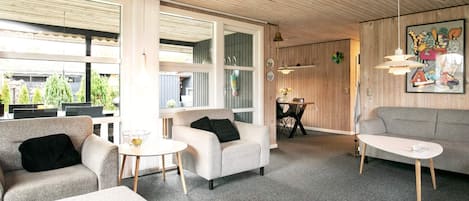 A modern interior with a sofa, armchairs, and a dining area.