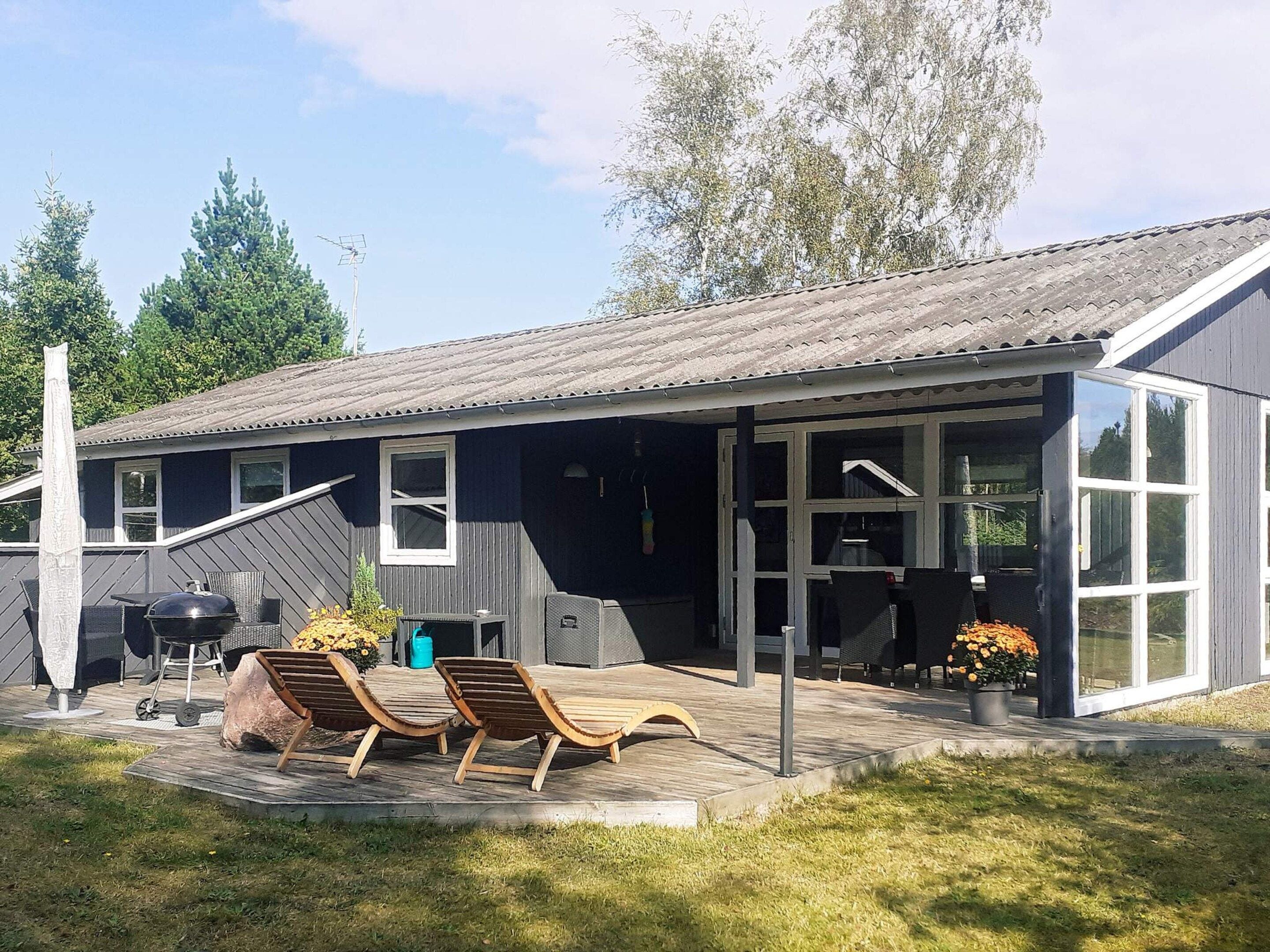 A modern house with a covered patio, outdoor seating, and a grill.