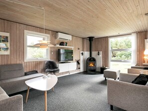 Uma sala de estar moderna com lareira, sofás, televisão e mesa de jantar.