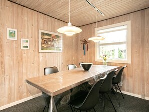 A conference room with a long table, black chairs, wooden walls, and a window with a view.