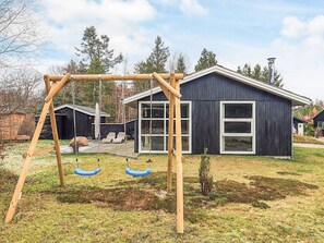 A modern house with a swing set in the yard.
