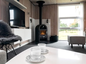Um interior moderno com lareira, um sofá e uma mesa de jantar com copos.