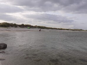 A beach with a tent and a person in the water.