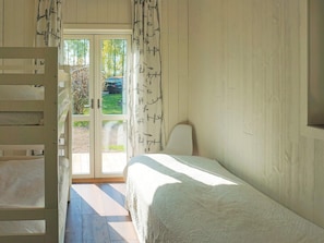 Un dormitorio con literas, una cama individual, un ventanal con cortinas y vistas al exterior.