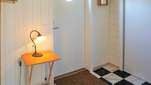 Een kamer met een deur, een tafeltje met een lamp, een spiegel en een geruit vloertje.