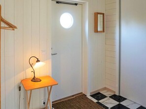 Una stanza con una porta, un piccolo tavolo con una lampada, uno specchio e un pavimento a scacchi.