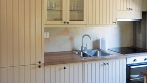 Een keuken met een dubbele spoelbak, roestvrijstalen apparatuur en lichtgekleurde kastjes.