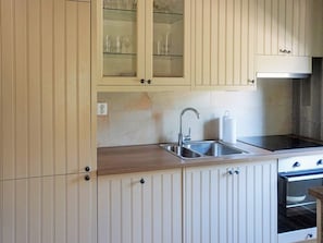 Una cucina con un lavello doppio, elettrodomestici in acciaio inossidabile e mobili chiari.