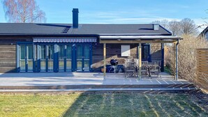 A modern building with a covered patio area, large glass doors, and outdoor seating. - 4 Star Holiday Home in Solvesborg (Sölvesborg)