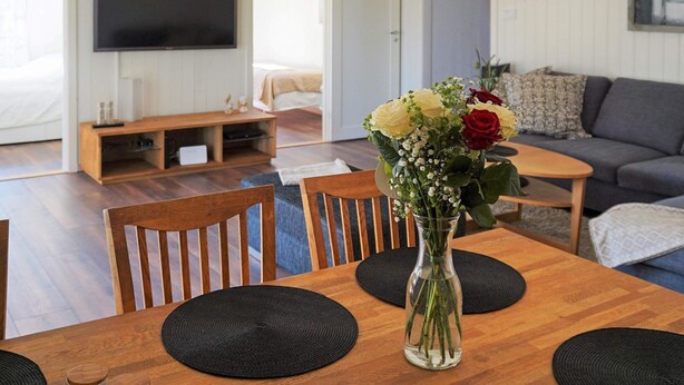 Een eetgedeelte met een houten tafel, stoelen en een bloevas.