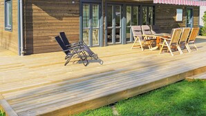 A wooden cabin with a deck, outdoor seating, and a covered patio area. - 4 Star Holiday Home in Solvesborg (Sölvesborg)