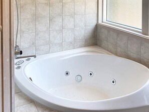 Un baño moderno con una bañera independiente, un cabezal de ducha y un ventanal que proporciona luz natural.