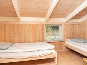 Una habitación pequeña con paneles de madera, dos camas y una ventana.