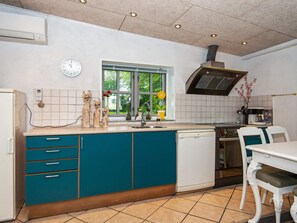 Une cuisine avec des meubles de couleur turquoise, un lave-vaisselle blanc et une fenêtre donnant sur un paysage verdoyant.