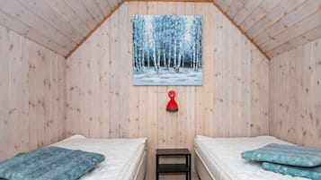 Una habitación con dos camas, una lámpara roja y un cuadro de un bosque nevado en la pared.