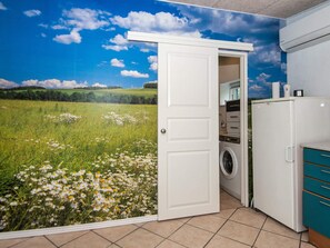 A room with a door leading to a field of flowers, a washing machine, and a white cabinet. - 4 Person Holiday Home in Skaerbaek (Skaerbaek)