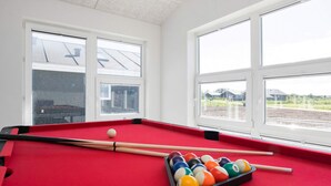 A pool table with balls and cues, large windows with a view of a field and buildings, and a ceiling with a textured finish. - 5 Star Holiday Home in Lokken (Lokken)
