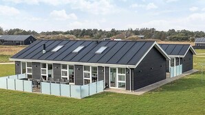 A modern building with a flat roof, large windows, and a covered outdoor seating area. - 5 Star Holiday Home in Lokken (Lokken)