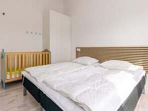 A bedroom with a bed, a crib, and a wardrobe. - 5 Star Holiday Home in Lokken (Lokken)