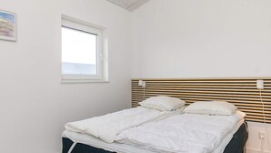 A bedroom with a bed, a window, and a wooden headboard. - 5 Star Holiday Home in Lokken (Lokken)