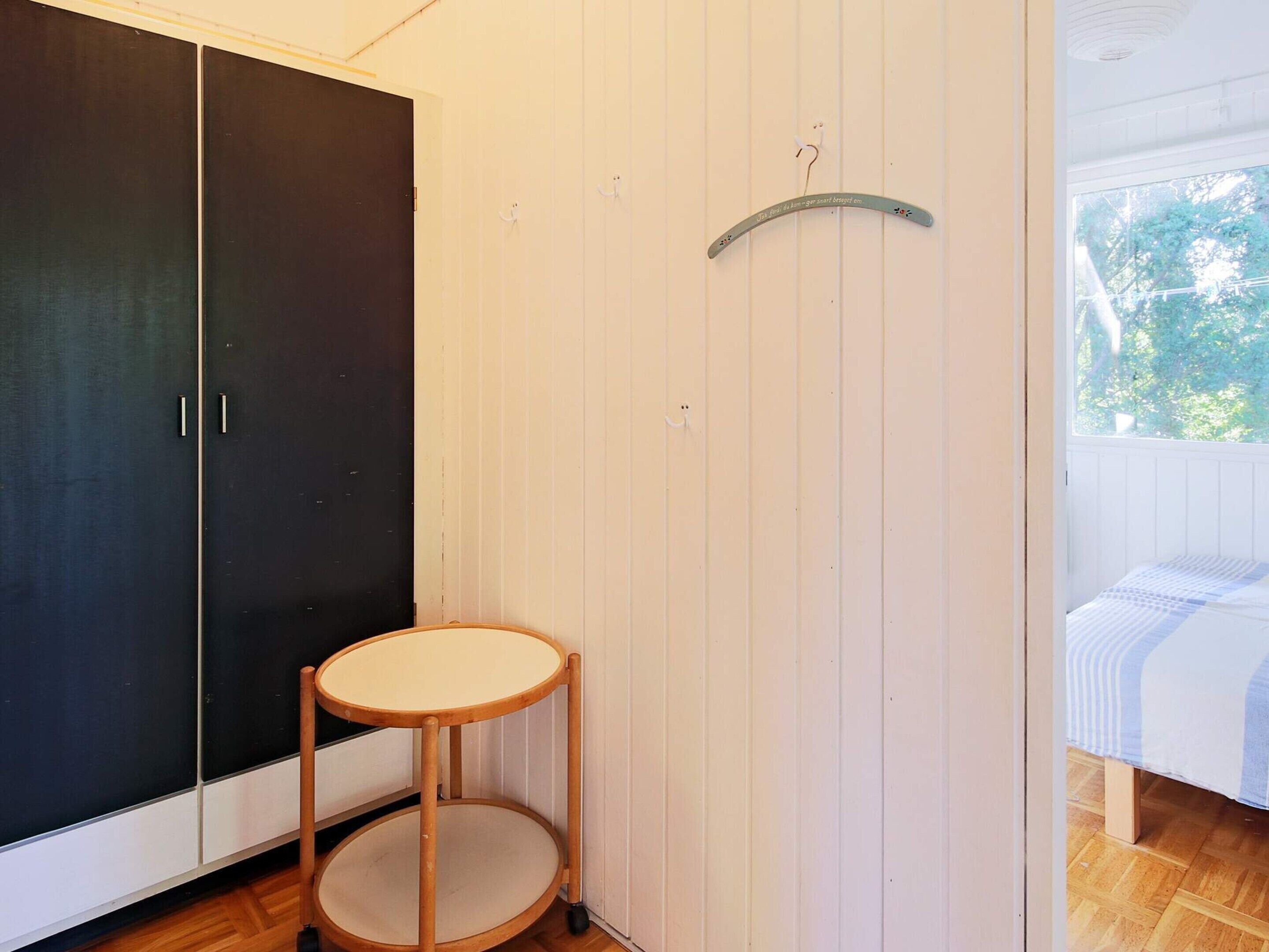 Ein Zimmer mit Kleiderschrank, einem runden Tisch und einem Bett mit gestreifter Bettdecke.