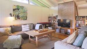 Un salon confortable avec un canapé, une table basse, une bibliothèque, un téléviseur et un billard.
