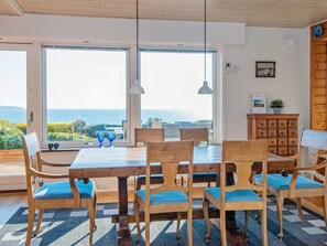 A dining area with a view of the sea, wooden furniture, and a cabinet with drawers. - 6 Person Holiday Home in Borkop (Borkop)