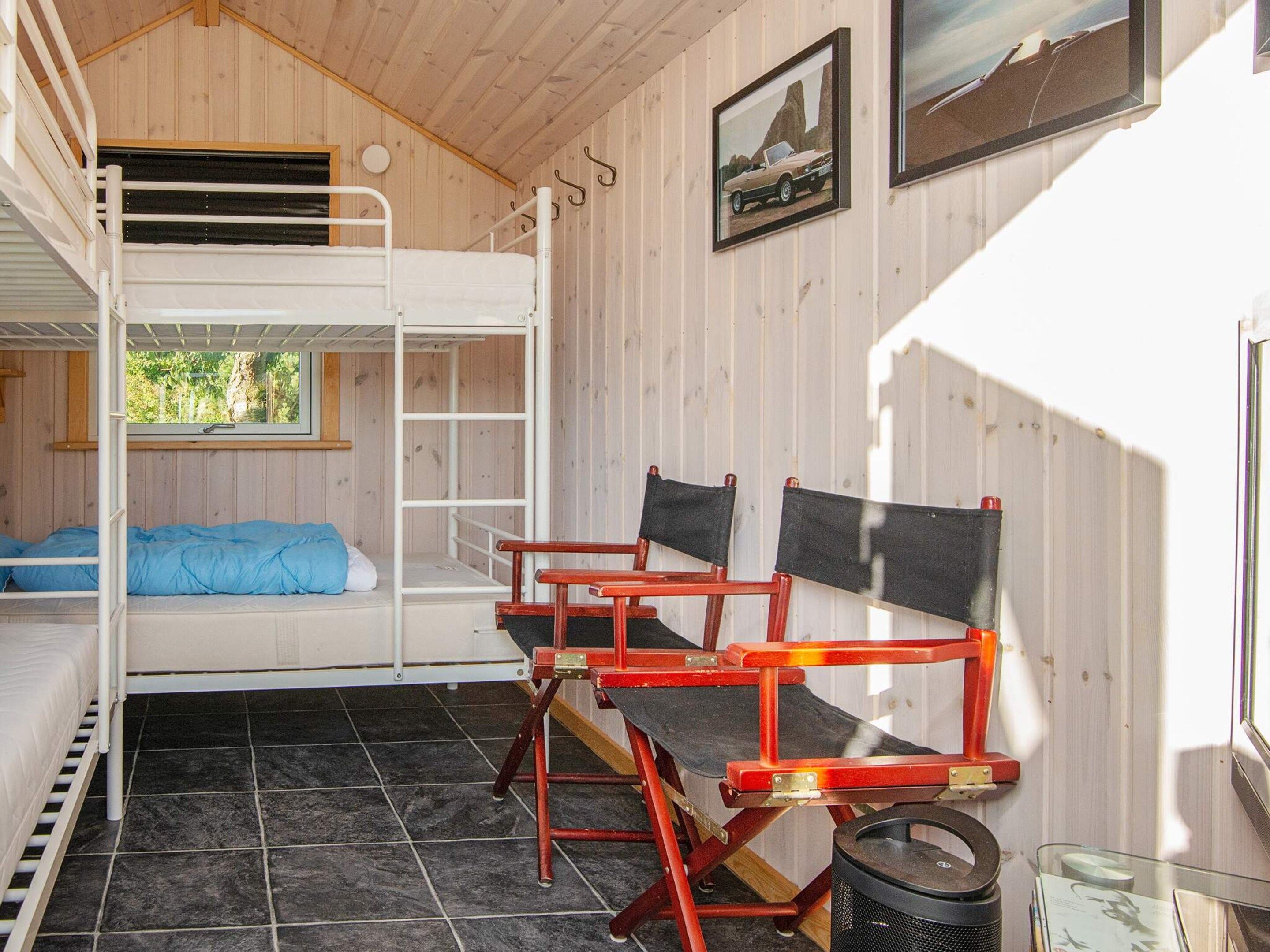 Uma cabana com beliche, um banco e uma janela.