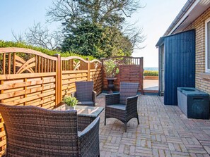 An outdoor patio area with wicker furniture and a brick floor.