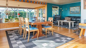 A spacious living area with a wooden dining table, chairs, and a sofa. There is a large window providing a view of the outdoors. - 6 Person Holiday Home in Borkop (Borkop)