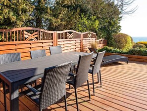 An outdoor deck with a dining table and chairs, surrounded by wooden fences and greenery. - 6 Person Holiday Home in Borkop (Borkop)