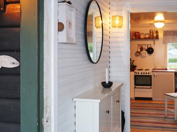 A compact kitchen with white cabinetry, a stove, and a hanging pot rack.