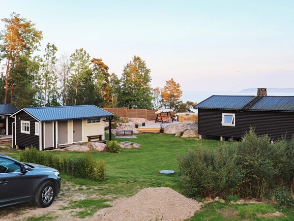 A campsite with cabins, a car, and a view of the sea.