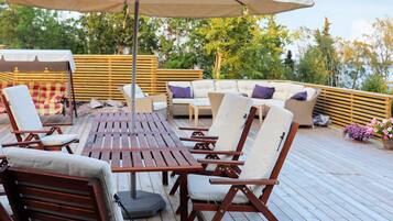 An outdoor deck with a wooden table, lounge chairs, and a sofa.