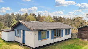 Une maison de plain-pied avec un toit à pignon, un petit garage attenant et une pelouse bien entretenue.