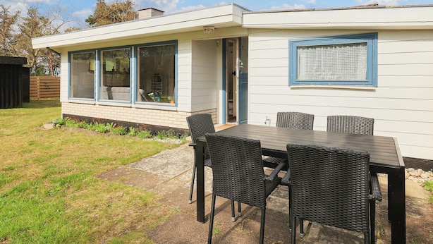 Une maison moderne dotée d’un patio comprenant une table et des chaises.