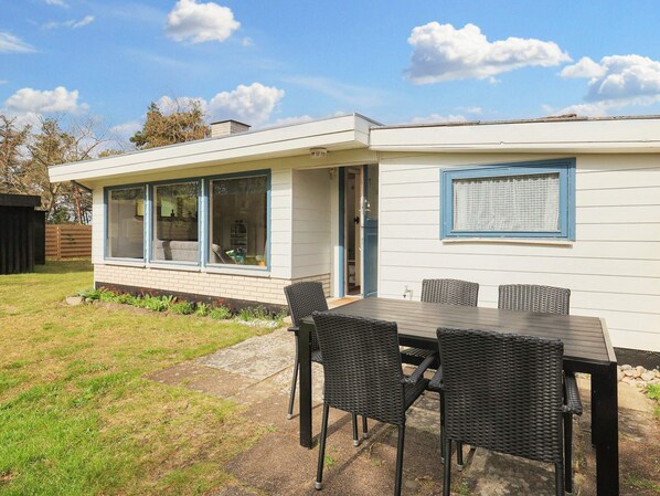 A modern house with a patio area featuring a table and chairs.