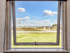 A window with a view of a coastal landscape, including a road and beach access signs.