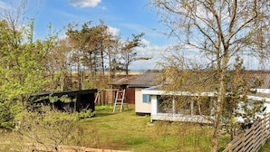 Il s’agit d’une propriété résidentielle dotée d’une cour clôturée, d’une terrasse en bois, d’un petit abri de jardin et d’une maison avec un toit en pente.