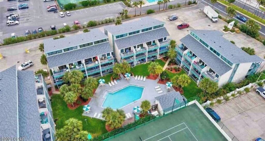 A hotel with multiple floors, a central swimming pool, and a tennis court.