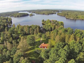 An aerial view of a lakeside property with a red house surrounded by dense forest and multiple lakes. - 6 Person Holiday Home in Aplared-by Traum (Aplared)
